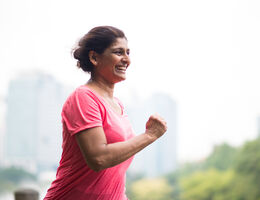 A woman runs outdoors, a blurry skyline behind her.
